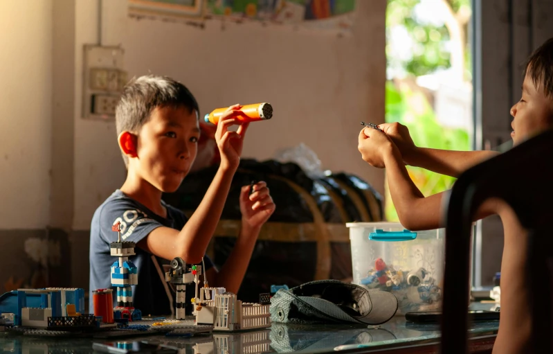 two boys are sitting at the table with toys