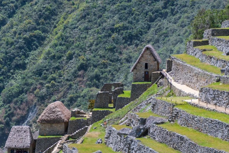 a stone structure next to a large grassy area with a building