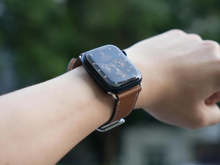 a brown leather apple watch band, with a floral design on it