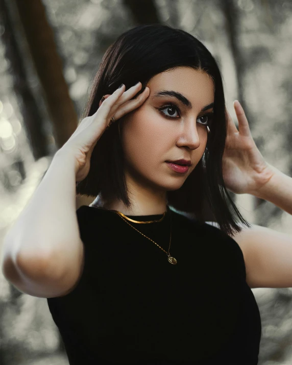 a woman in a black dress holding her hair