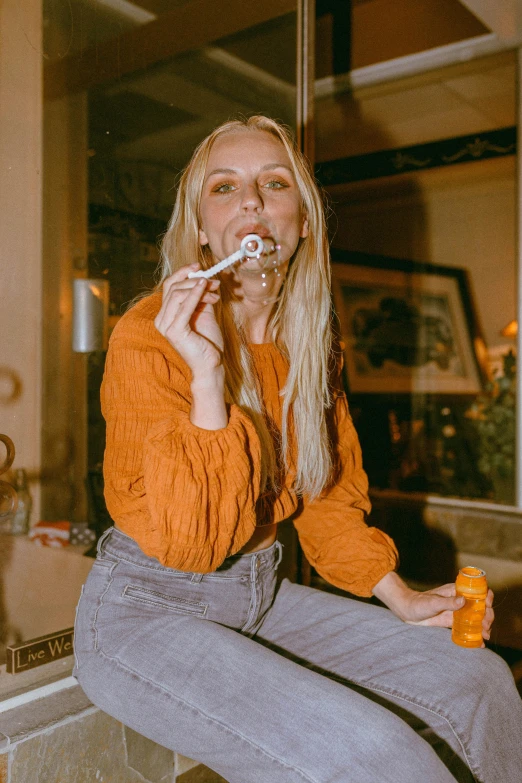 a woman sitting on top of a kitchen counter brushing her teeth