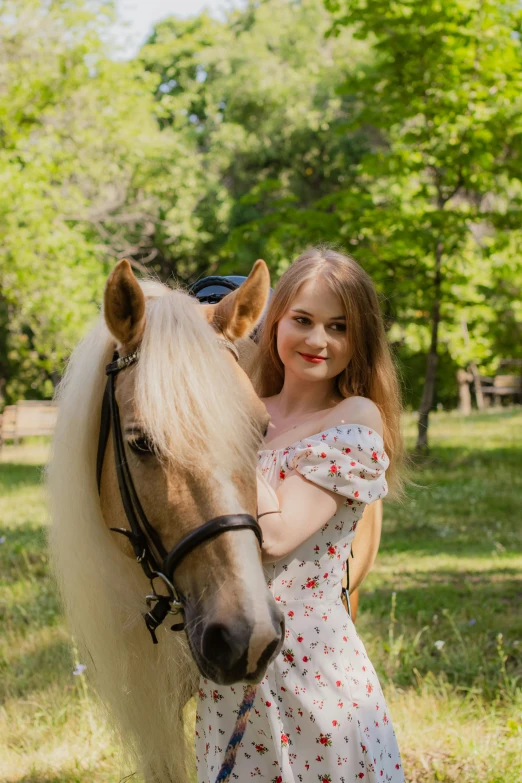 a girl standing next to her horse in the grass