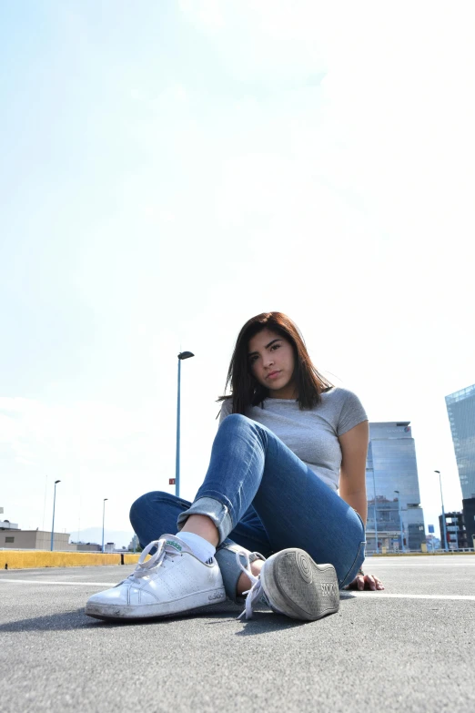 a beautiful woman sitting down in front of an empty parking lot