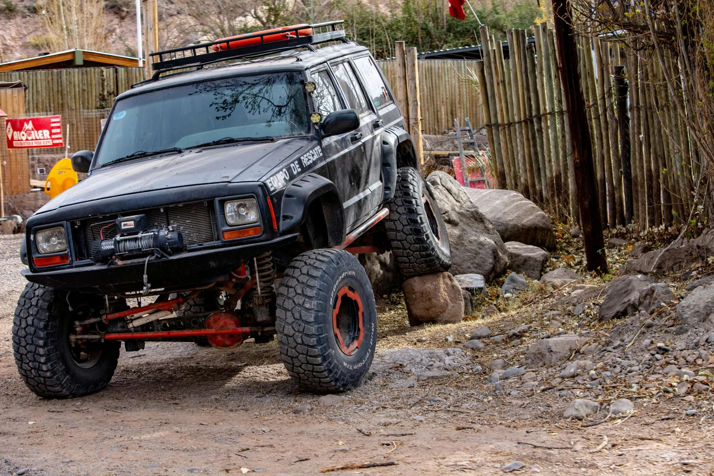 the car is parked near a pile of rocks and logs