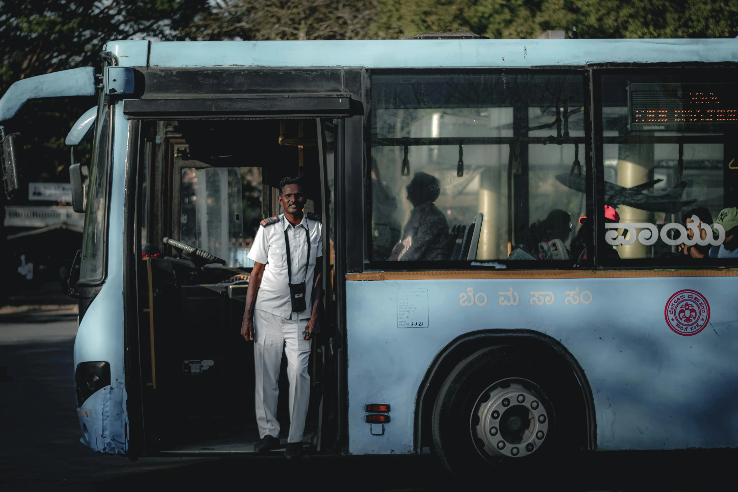 a man with a neck tie is standing next to a bus