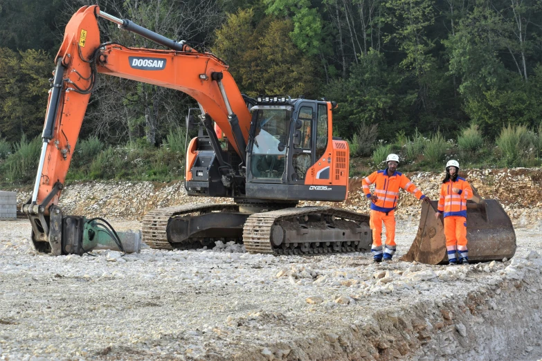 two men are standing next to two orange tractors