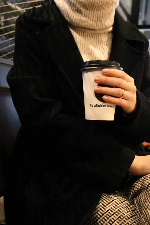 a woman sitting on the bus and holding her coffee in her hand
