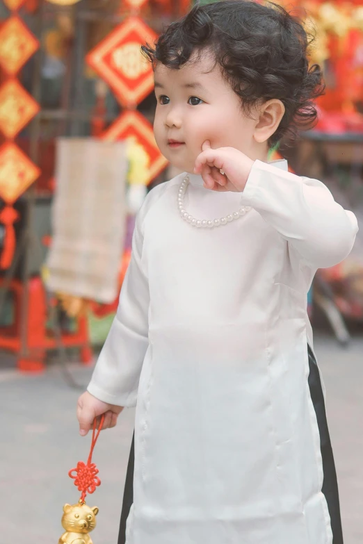 a little girl in a white dress holds a golden flower and a small figure