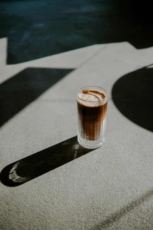 a glass of liquid sitting on the ground