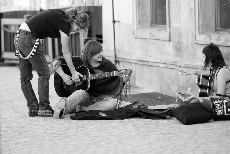 a woman is playing guitar next to another woman