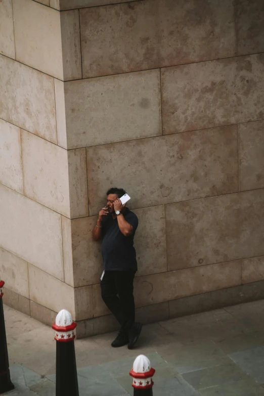 a man standing next to a building while talking on a cell phone