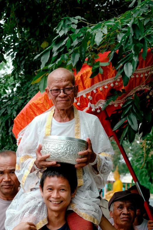 an old man is holding a silver bowl in the street