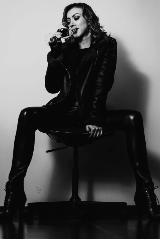 woman drinking from a glass with black leather pants and thigh high boots