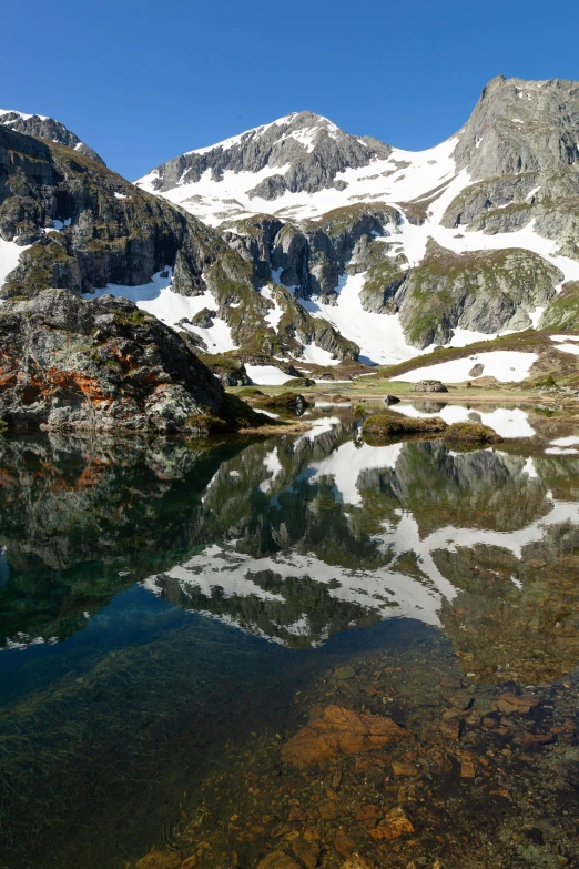 snow covered mountains reflect in the still water