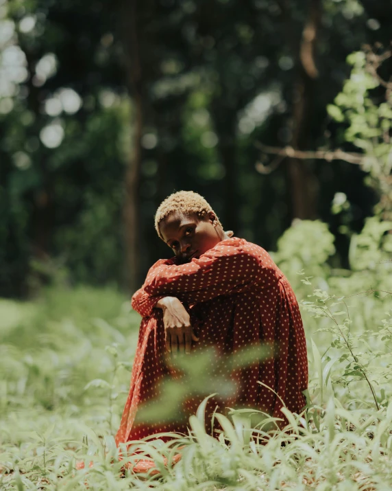 the woman is sitting in the tall grass by the trees