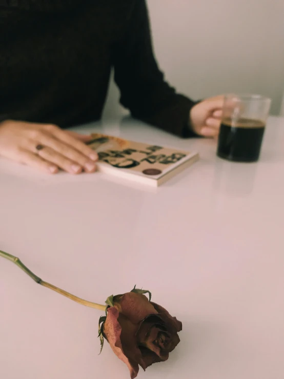 someone at a table with a rose and book