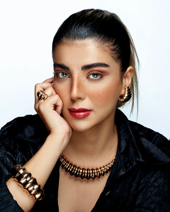 young woman wearing gold jewelry posing for a po