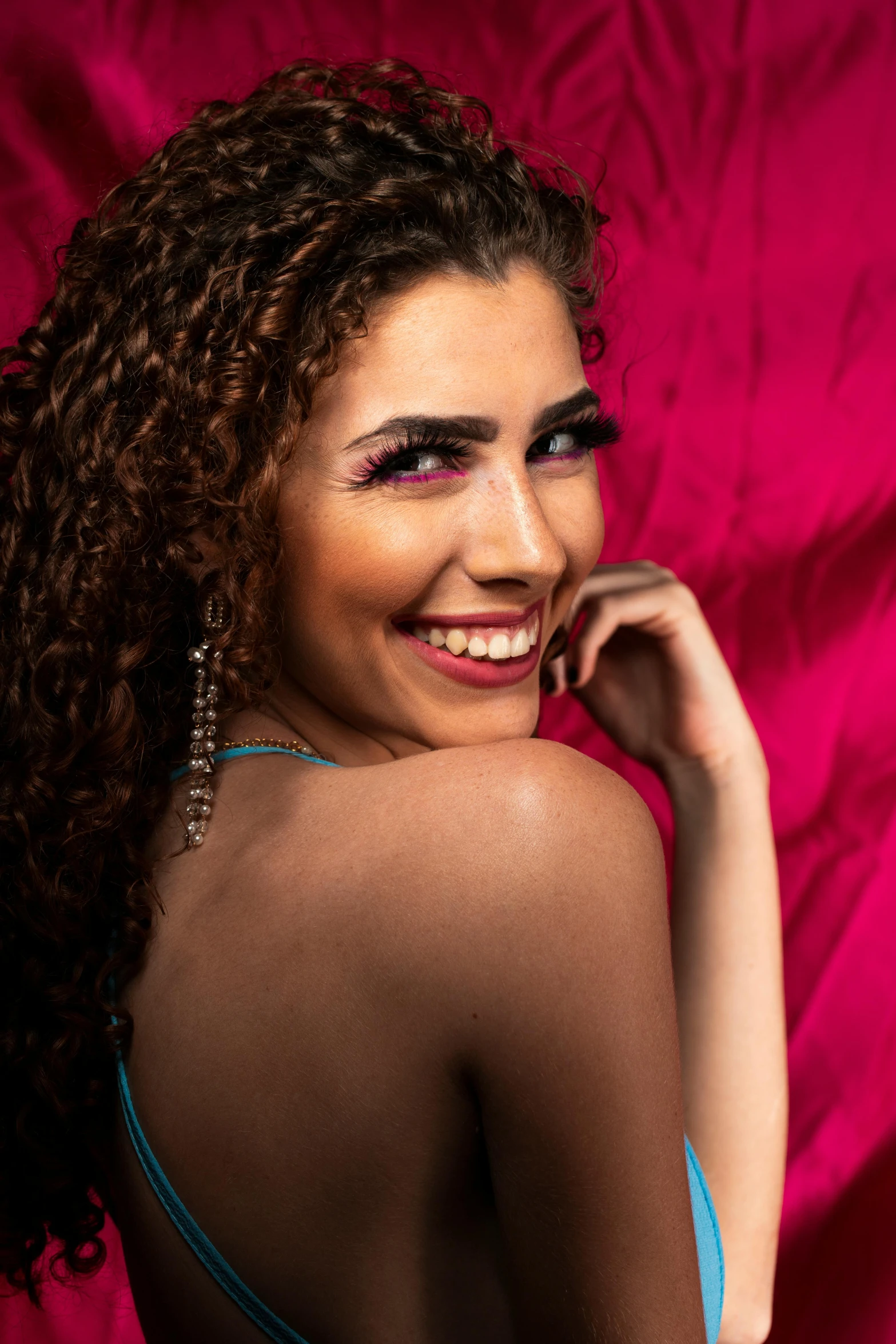 a woman in a blue swimsuit has her hair styled with eye shadows and a pink lip