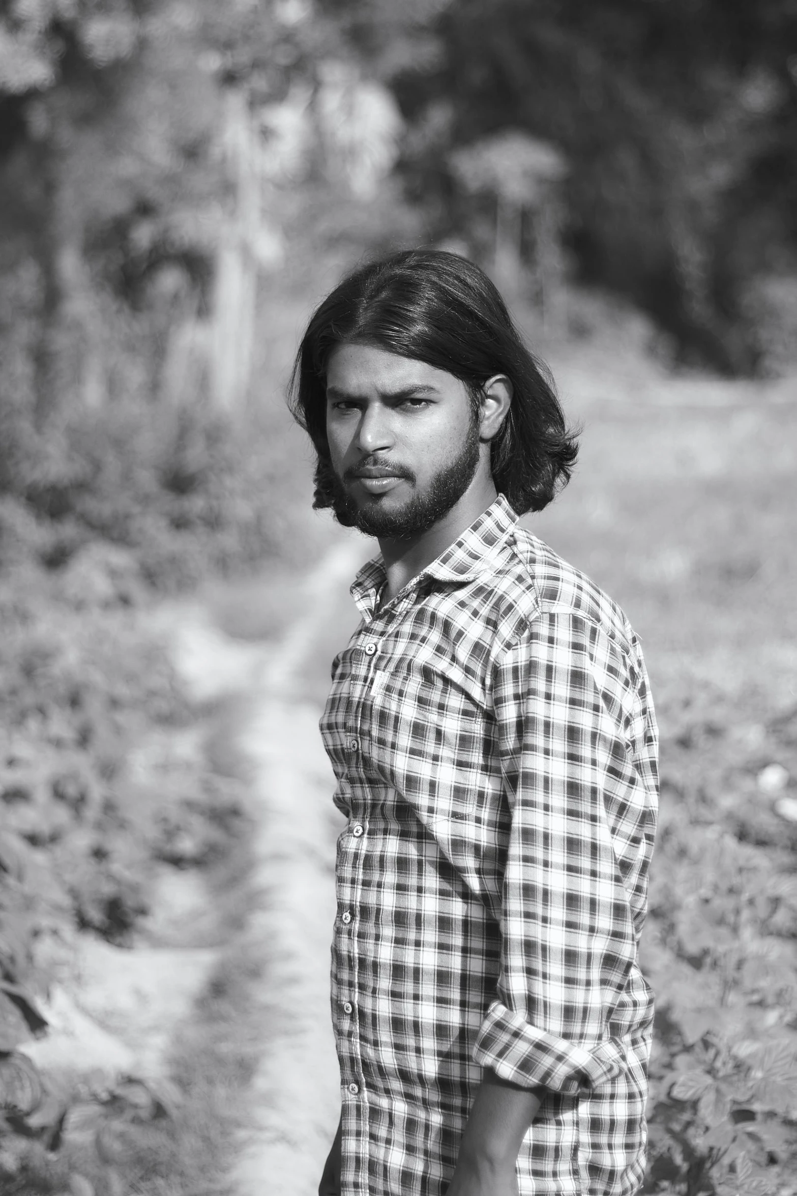 a man with long hair standing in a field