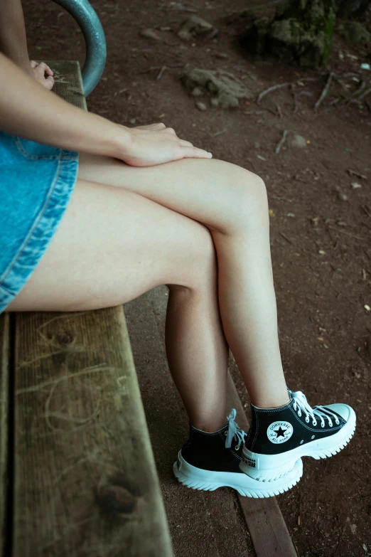 the girl's legs are stretched out on a park bench