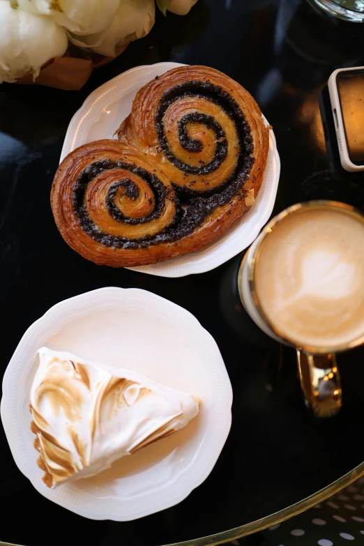 three pastry items on plates next to some coffee