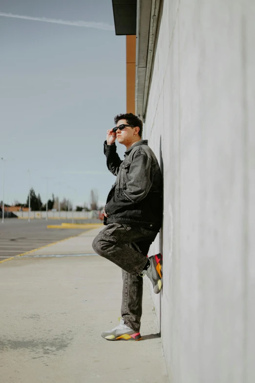 a man leaning against the side of a building and talking on his phone