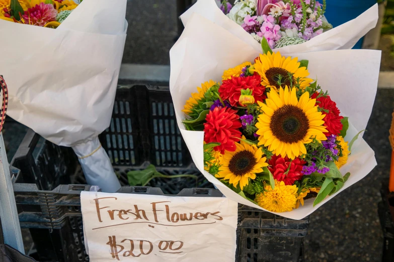 two bouquets of fresh flowers for sale are in a crate