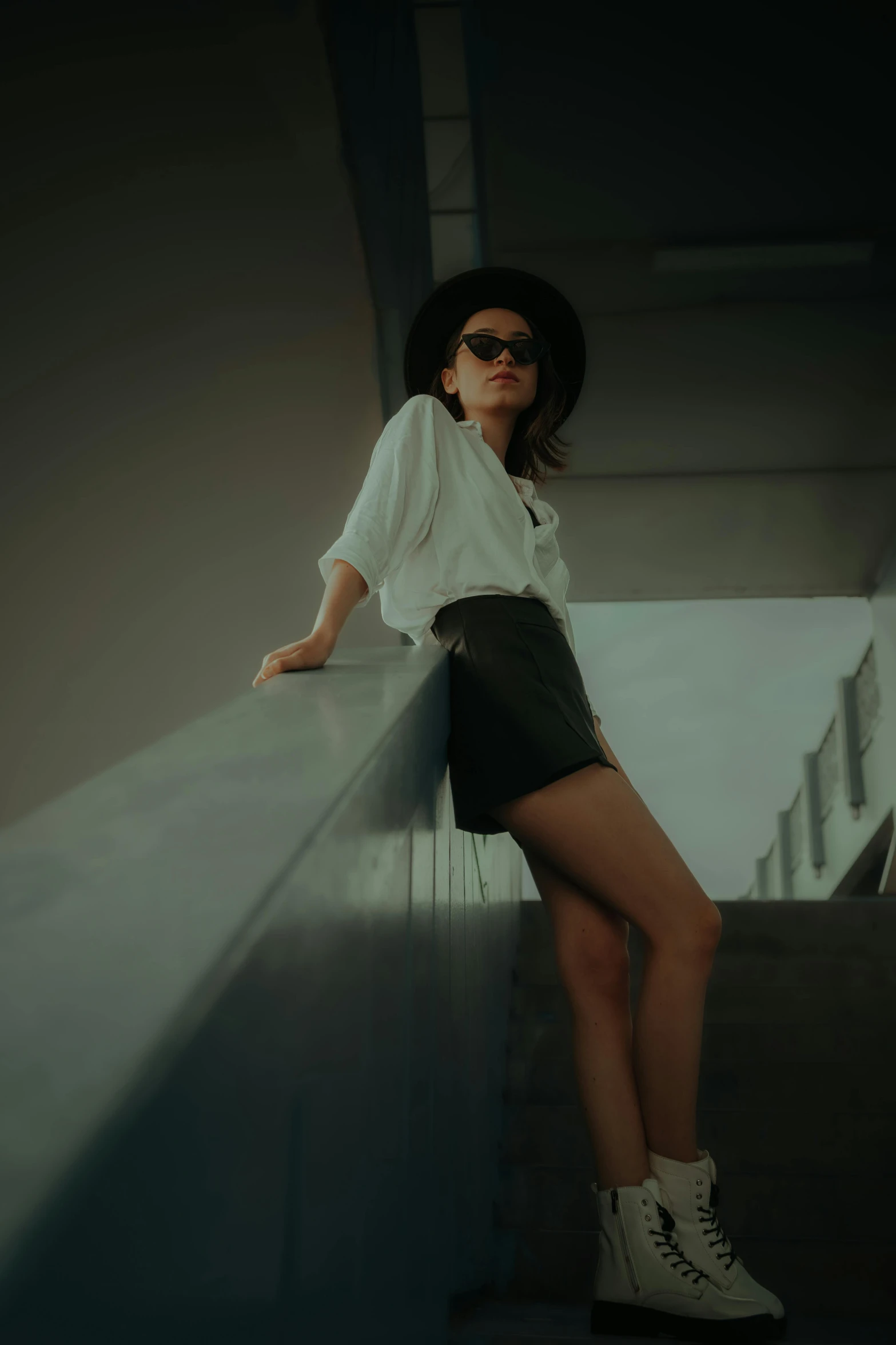 woman wearing a hat and sunglasses standing on a set of stairs