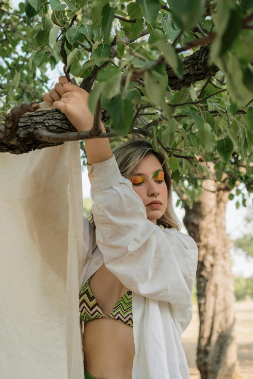 a woman in a bikini and green patterned panties climbs a tree nch