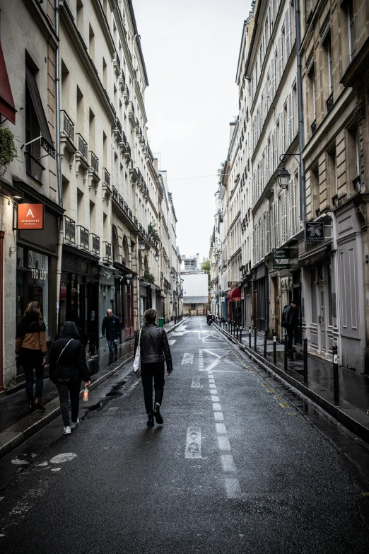 several people walk down an empty street with buildings