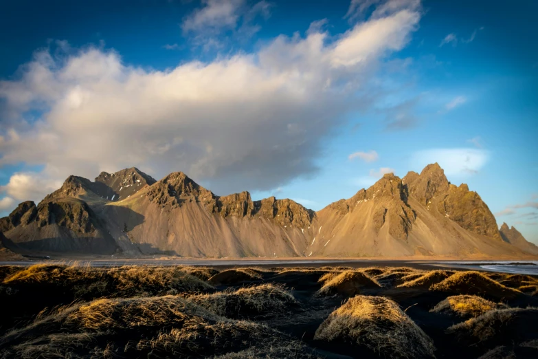 some very tall mountains under a blue cloudy sky