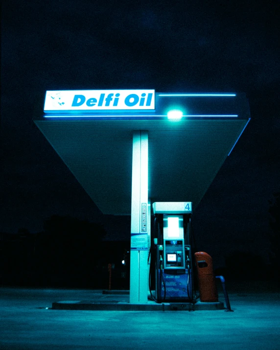 a gas station with a blue lighted sign at night