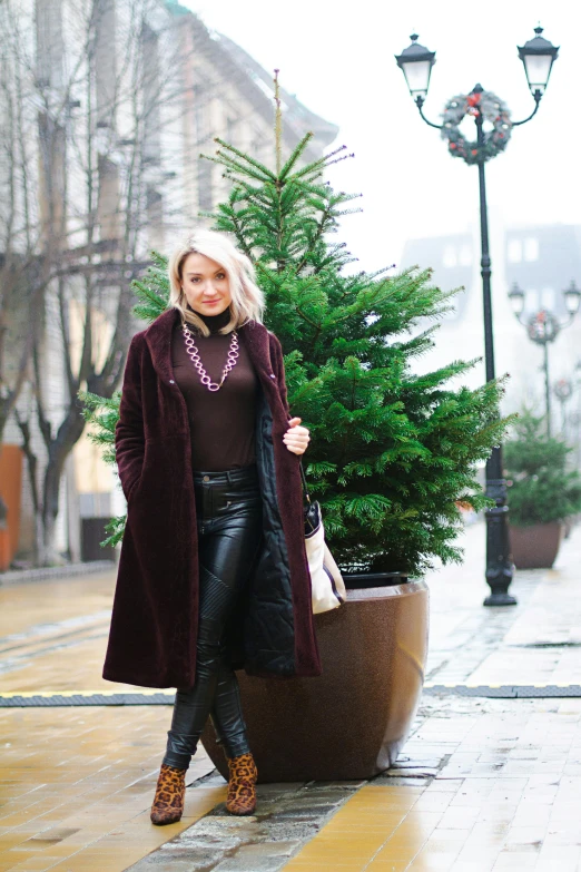 a woman is holding an umbrella and a small christmas tree