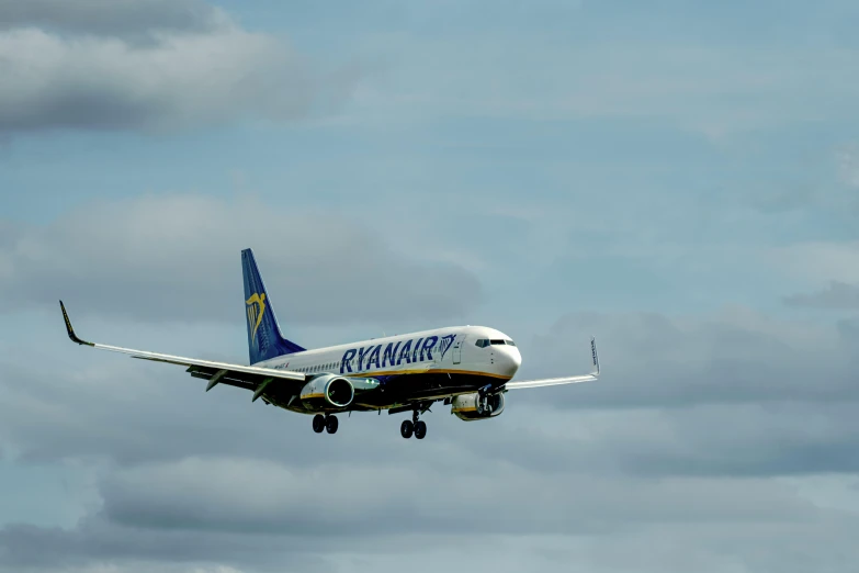 a white, blue and gold plane is flying in the air