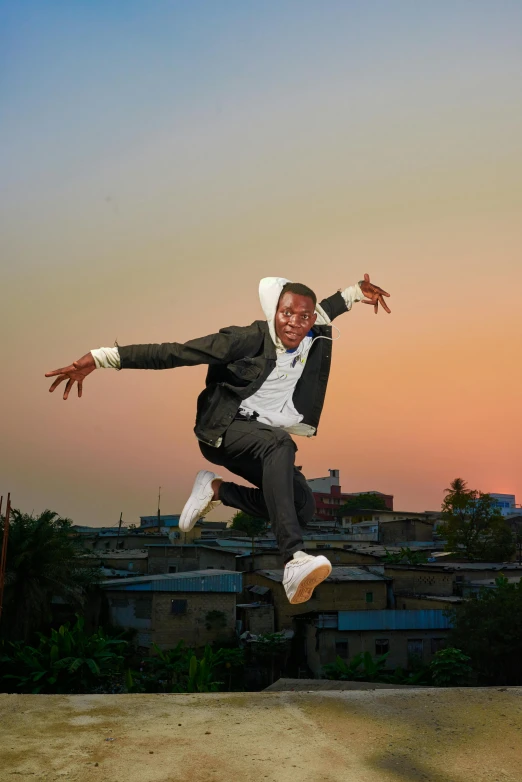 a young man wearing a suit and hoodie jumps in the air while jumping into the air with his hands outstretched wide open