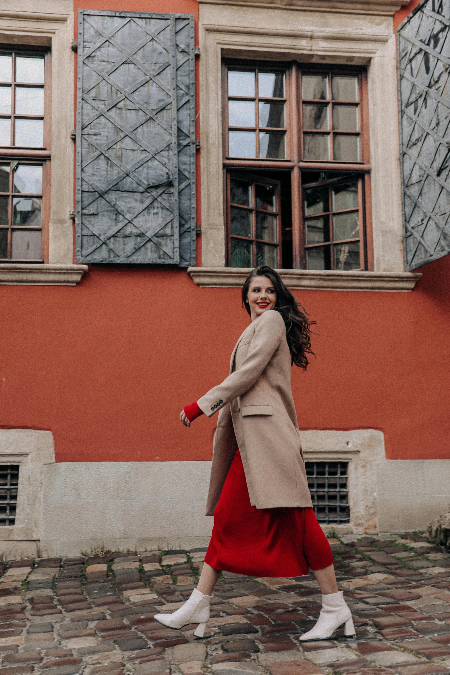 woman in beige coat walking down the street