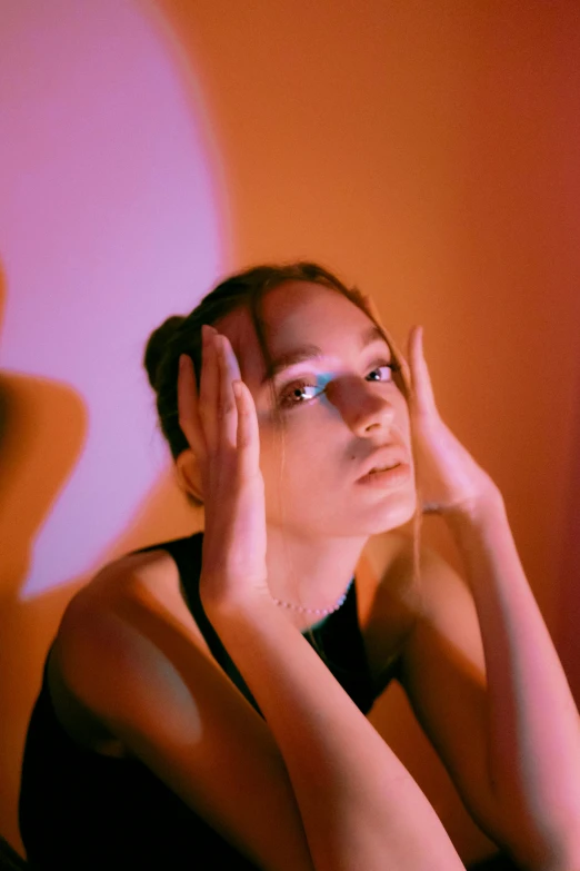 a young lady is sitting with her hand under her ears