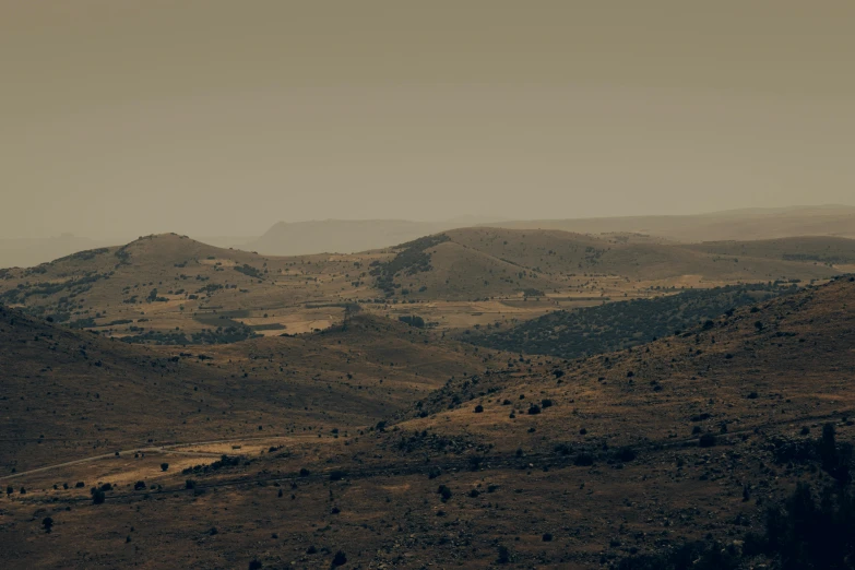 a dirt and grass covered hillside, with hills in the distance