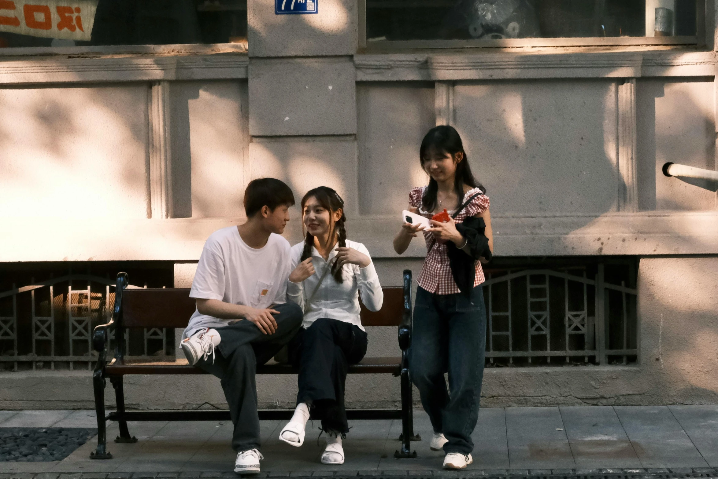 three people sitting on a bench and looking at their cellphones