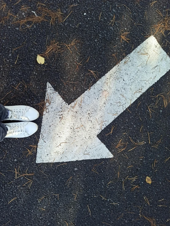 two fingers point to a direction sign on the ground