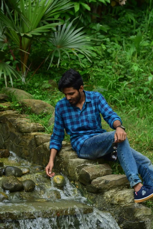 a man sitting by the side of the stream