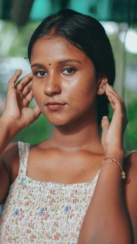 a young woman holding her hand near her ear