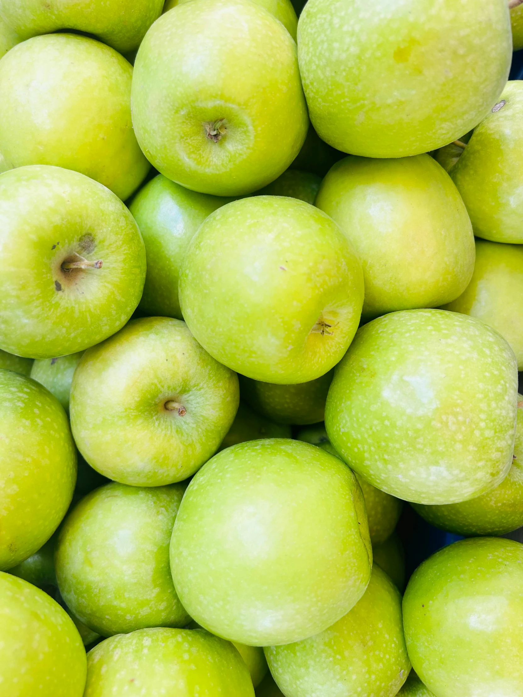 green apples stacked on top of each other in rows