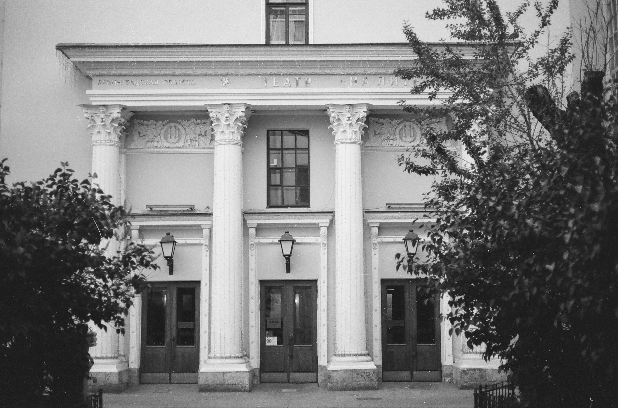 a white building with columns and trees in front