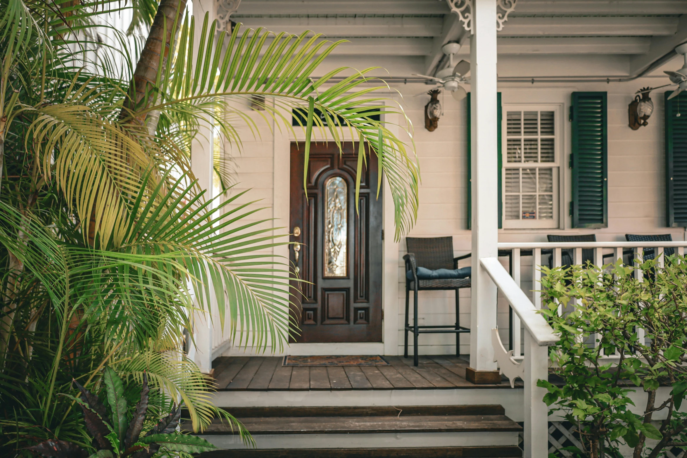 a porch with steps, chair and palm tree in front