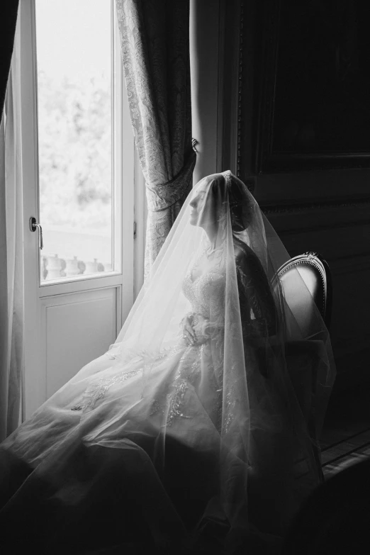 a bride's veil hanging off the back of a chair in front of a window