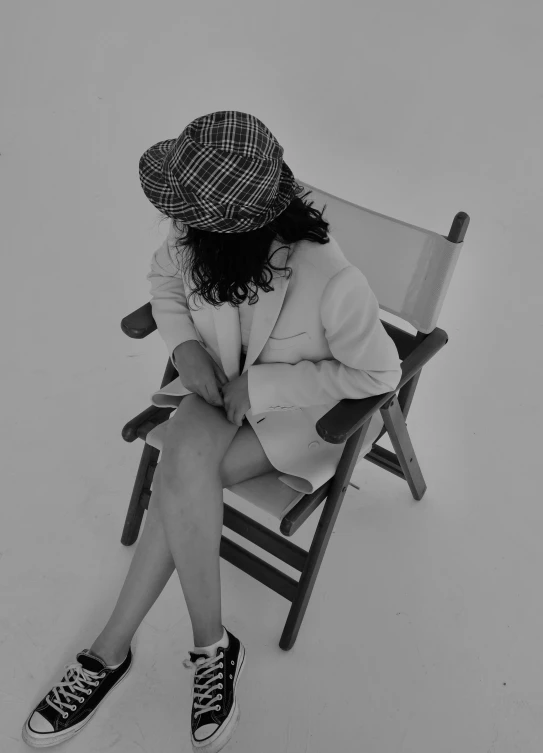 a woman in a hat and coat sitting on a chair