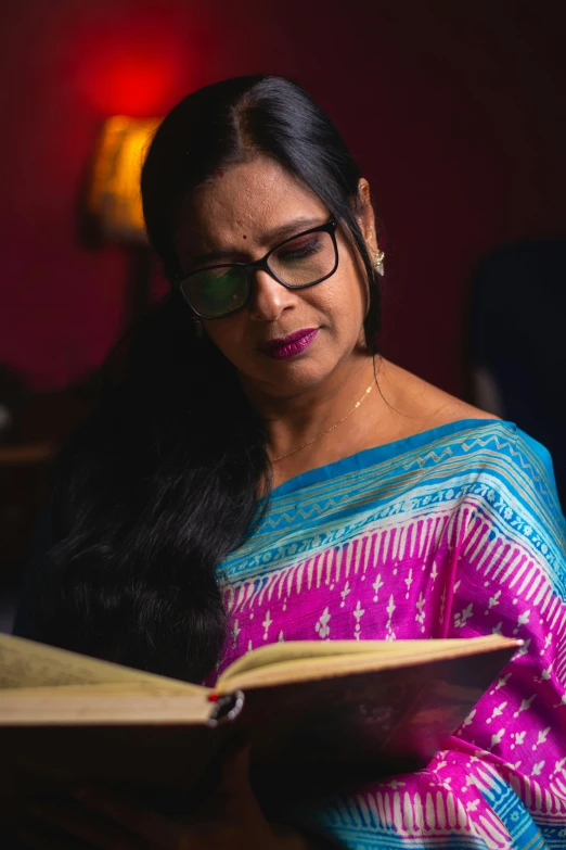 woman wearing glasses while reading a book in the dark