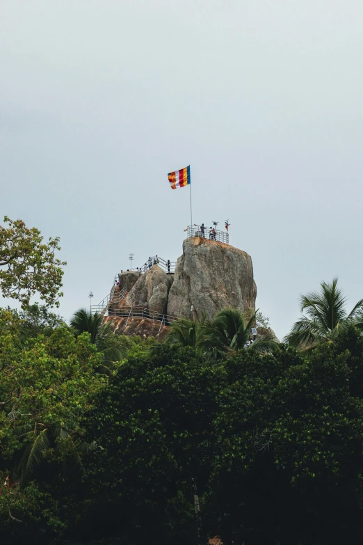 two flags sticking out from top of a large rock