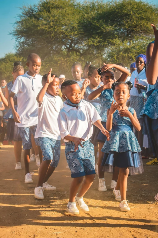 young children are playing with a blue frisbee in front of people